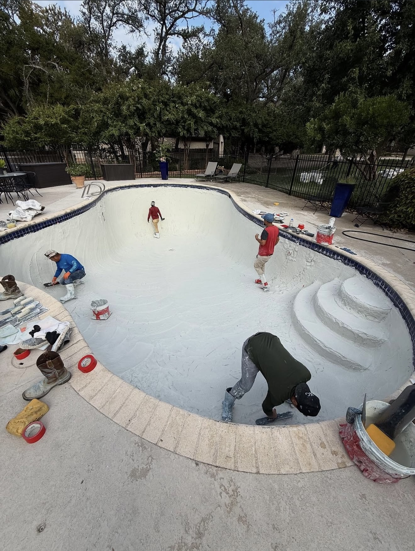 The Texas Tide Pool Service crew troweling fresh plaster inside a backyard pool