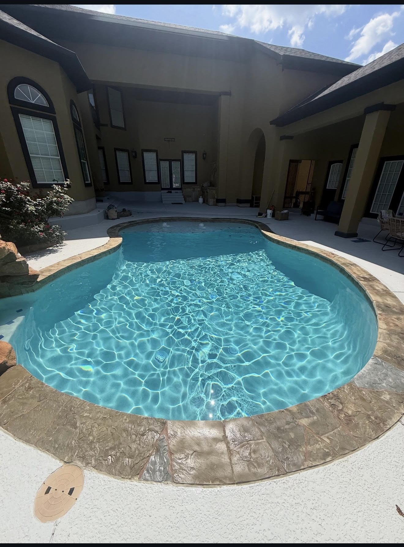 Freeform pool with fresh finish beside a Hill Country home