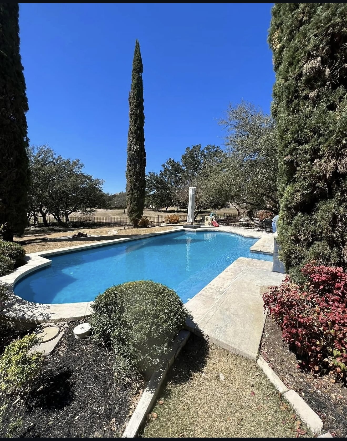 Restored pool with stamped concrete decking and clear blue water
